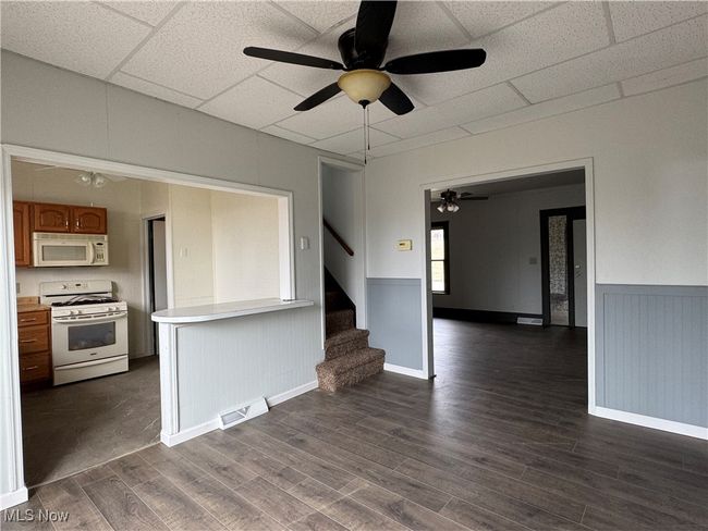 Unfurnished living room with ceiling fan, a paneled ceiling, and dark hardwood / wood-style flooring | Image 5