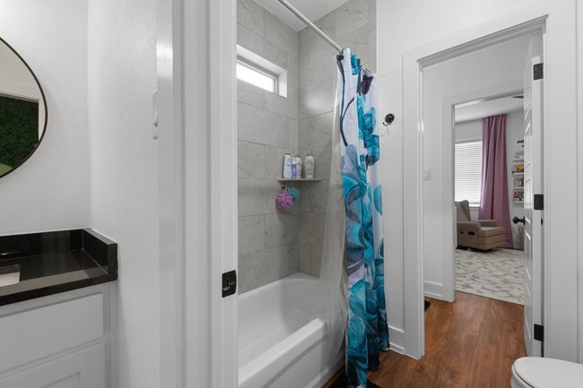 Bathroom with toilet, shower / tub combo, wood finished floors, and vanity | Image 32