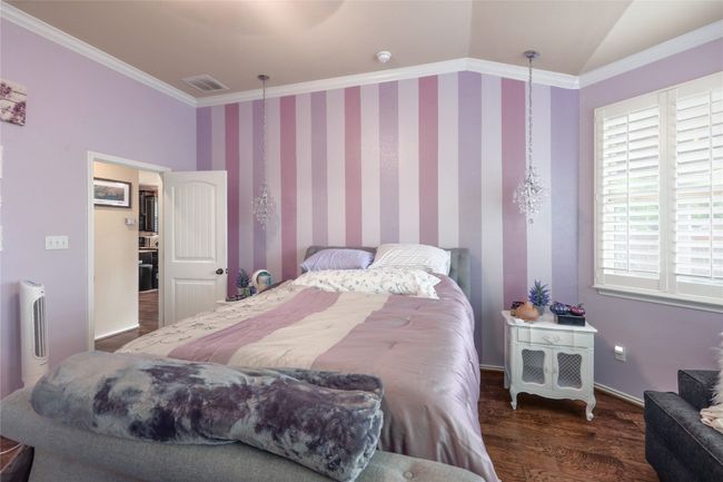 Bedroom with wood finished floors, crown molding, lofted ceiling, and baseboards | Image 16