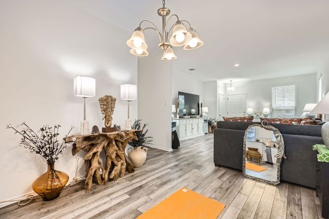 Living area with light wood finished floors and a chandelier | Image 12