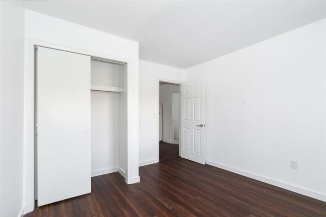 Unfurnished bedroom featuring dark wood-style flooring, a closet, and baseboards | Image 9