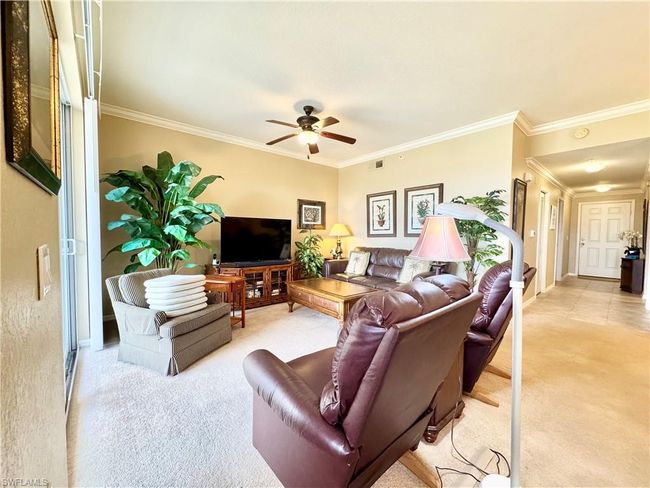 Living area featuring a ceiling fan, light carpet, baseboards, visible vents, and ornamental molding | Image 4