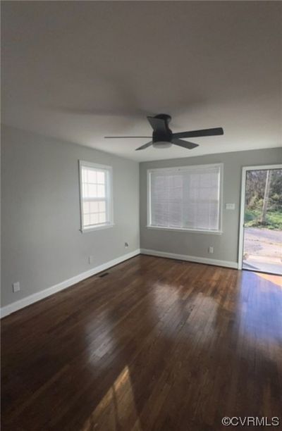 Empty room featuring dark wood-type flooring, ceiling fan, and plenty of natural light | Image 3