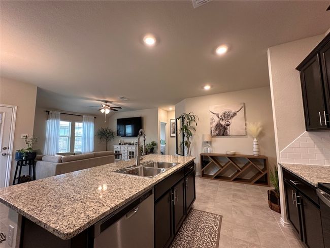 Kitchen with stainless steel dishwasher, a sink, a kitchen island with sink, open floor plan, and light stone counters | Image 20