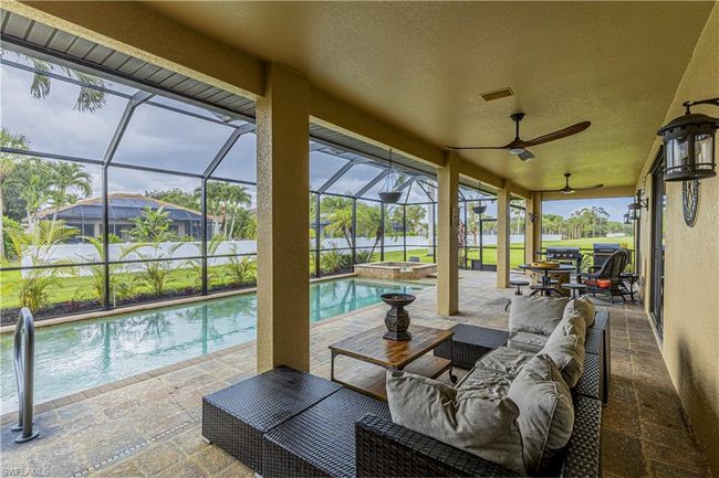 View of patio / terrace with glass enclosure, a ceiling fan, a pool with connected hot tub, and an outdoor hangout area | Image 25