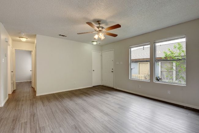 Empty room featuring ceiling fan, wood finished floors, a textured ceiling, and baseboards | Image 6