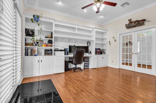 Office area with a ceiling fan, built in study area, crown molding, french doors, and light wood-style floors | Image 26