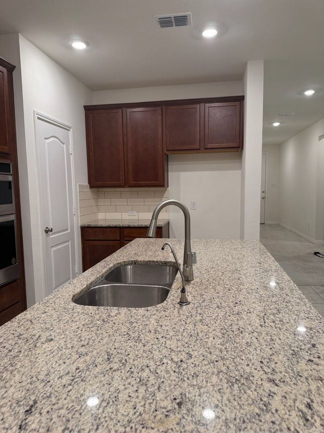 Kitchen with light stone counters, recessed lighting, decorative backsplash, and stainless steel double oven | Image 7