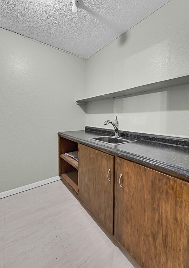 Bar with a sink, a textured ceiling, and baseboards | Image 16