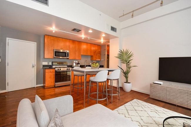 Blending the kitchen, dining, and living areas, this open loft condo offers a spacious layout perfect for entertaining or relaxing. Wood flooring, and natural light tie the space together beautifully. | Image 8