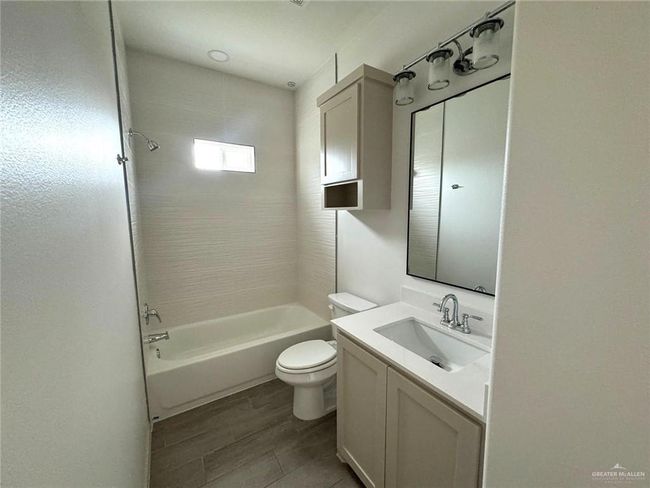 Bathroom with vanity, wood tiled floor, toilet, and shower / washtub combination | Image 11