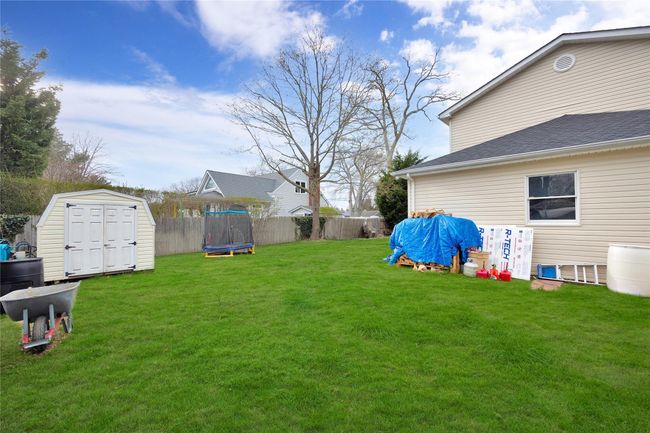 View of yard with a storage unit, an outdoor structure, fence, and a trampoline | Image 19