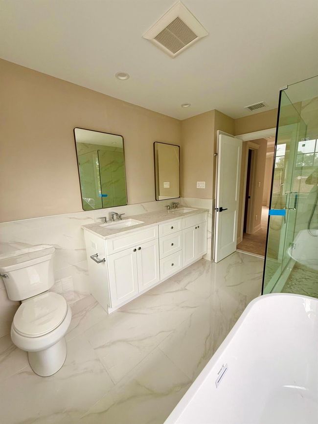Full bathroom with marble finish floors, a marble finish shower, double vanity, wainscoting, and a freestanding tub | Image 8