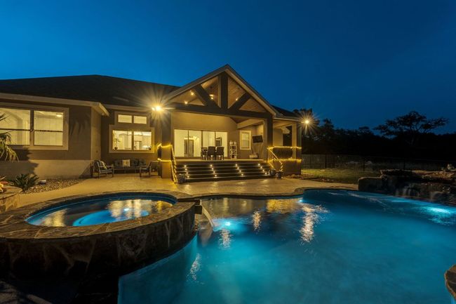 Pool at twilight with a patio area and a pool with connected hot tub | Image 30