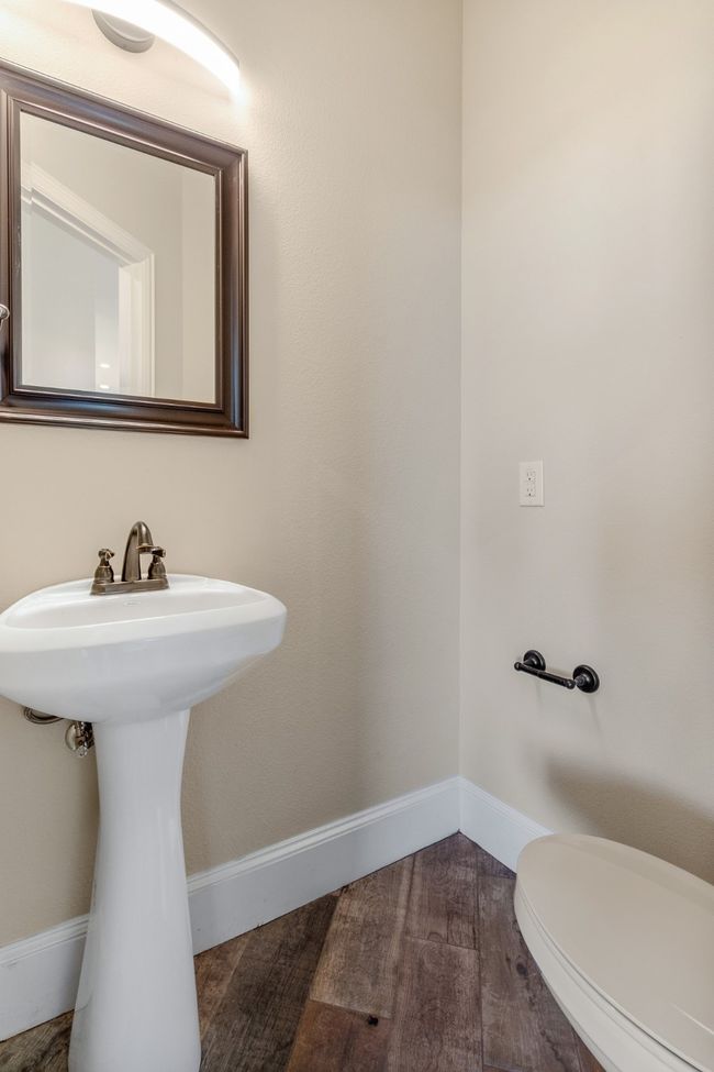 Bathroom with baseboards, wood finished floors, toilet, and a sink | Image 13