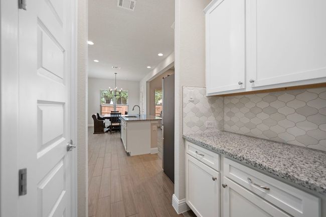 Kitchen featuring a sink, tasteful backsplash, light wood-style floors, white cabinets, and recessed lighting | Image 12