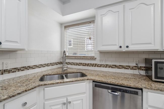 Kitchen featuring white cabinets, tasteful backsplash, a sink, and dishwasher | Image 9