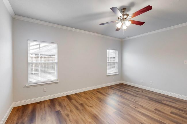 Empty room with crown molding, wood-type flooring, and ceiling fan | Image 9