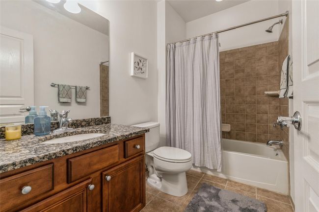 Bathroom with toilet, vanity, tile patterned flooring, and shower / bath combo with shower curtain | Image 8