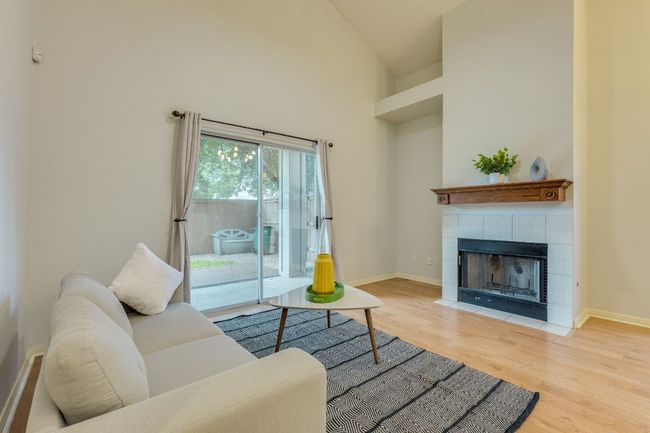 Living room featuring wood finished floors, a fireplace, and a high ceiling | Image 11