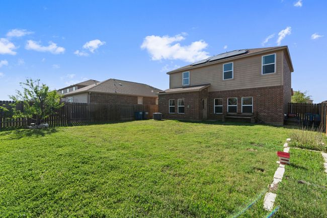 Back of house featuring central AC unit, a fenced backyard, a yard, solar panels, and brick siding | Image 34