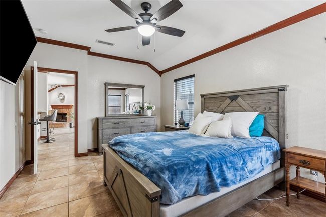 Bedroom featuring light tile patterned floors, baseboards, visible vents, vaulted ceiling, and crown molding | Image 4