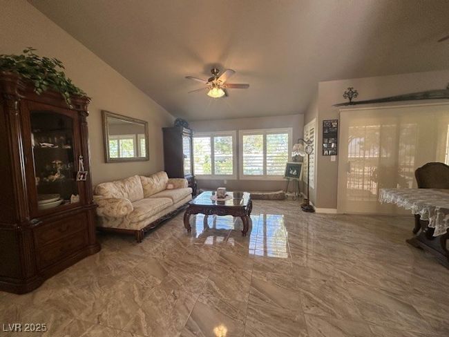 Living area featuring lofted ceiling, ceiling fan, and marble finish flooring | Image 4