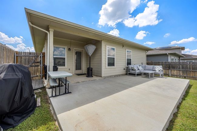 The covered back patio, perfect for outdoor dining or lounging, with a large concrete slab that extends the living space outdoors. | Image 26