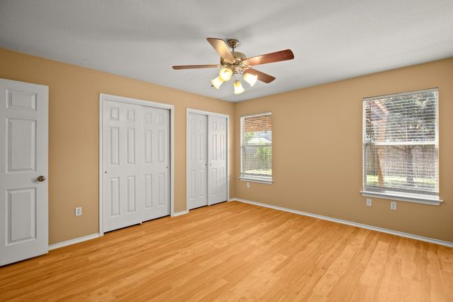 Unfurnished bedroom with multiple closets, light wood-style floors, baseboards, and a ceiling fan | Image 12