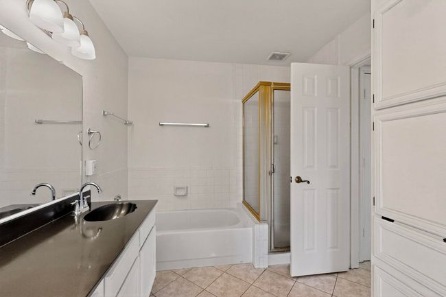 Bathroom with tile patterned flooring, a shower stall, a garden tub, vanity, and tile walls | Image 25