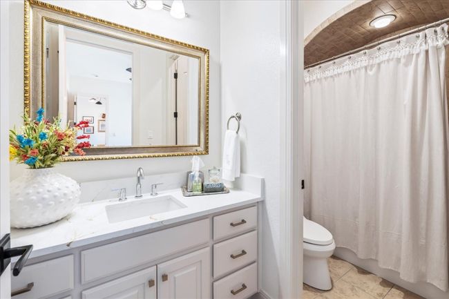 Bathroom with toilet, vanity, tile patterned flooring, and a shower with shower curtain | Image 26