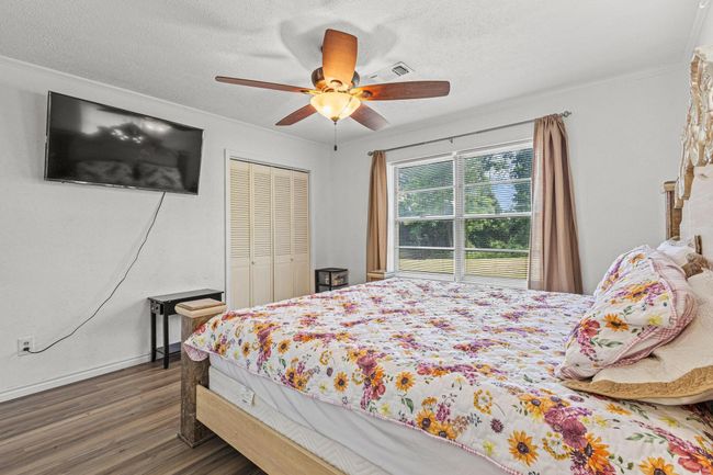 Bedroom featuring wood finished floors, a textured ceiling, crown molding, a ceiling fan, and a closet | Image 24