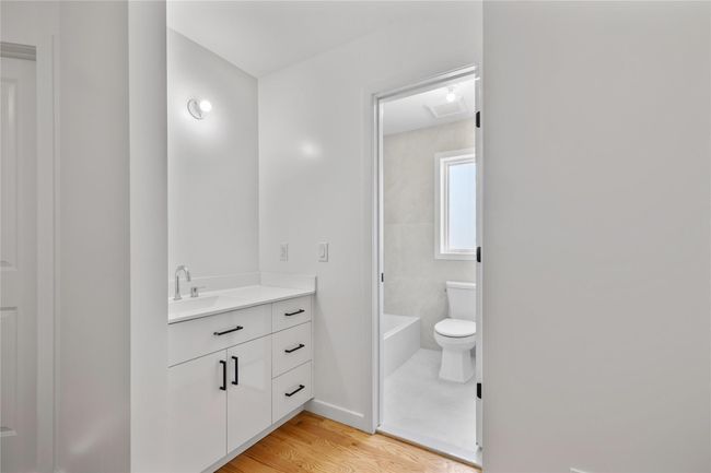 Full bathroom with a bath, toilet, baseboards, wood finished floors, and vanity | Image 34