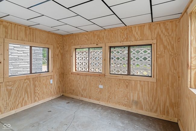 empty room with wooden walls, unfinished concrete flooring, and baseboards | Image 43