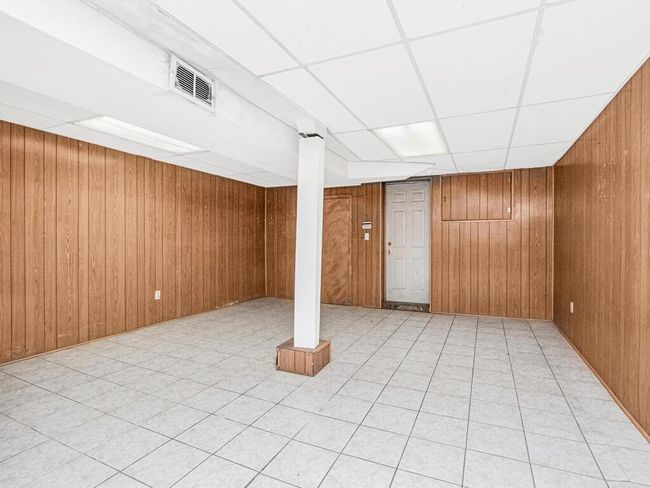 Finished basement with wood walls, visible vents, and a drop ceiling | Image 18