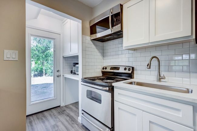 Kitchen with white cabinets, light wood finished floors, a sink, and appliances with stainless steel finishes | Image 5