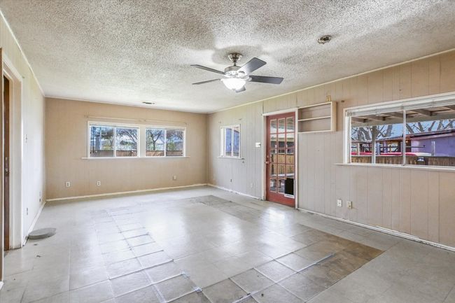 Spare room featuring wood walls, a textured ceiling, baseboards, and a ceiling fan | Image 6