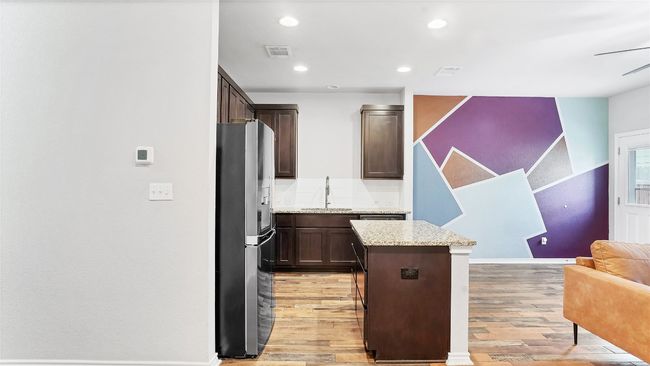 Kitchen with stainless steel fridge with ice dispenser, a center island, light wood finished floors, and visible vents | Image 14