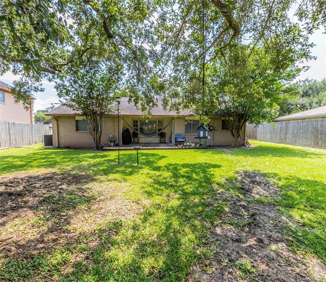 Charming backyard with a spacious lawn, shaded by large trees. Features a patio area perfect for relaxation and Ideal for outdoor activities and entertaining. | Image 29
