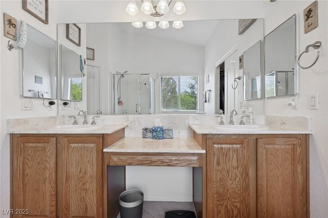 Full bathroom with a stall shower, two vanities, lofted ceiling, tile patterned floors, and backsplash | Image 54