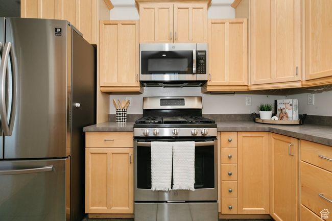 Kitchen featuring appliances with stainless steel finishes, light brown cabinets, and dark countertops | Image 7