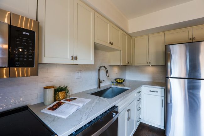 Kitchen with stainless steel appliances, light stone quartz countertops, backsplash, and dark engineered hardwood flooring. | Image 12