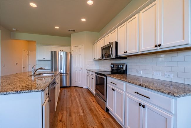 Kitchen with stainless steel appliances, recessed lighting, light wood-style flooring, white cabinetry, and decorative backsplash | Image 8