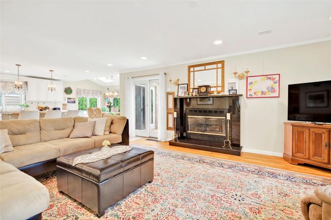 Living area featuring a chandelier, light wood finished floors, a glass covered fireplace, recessed lighting, and baseboards | Image 12