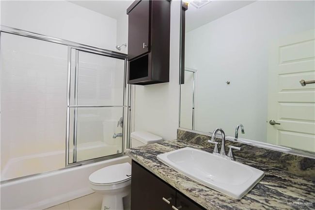 Bathroom with bath / shower combo with glass door, vanity, and toilet | Image 16