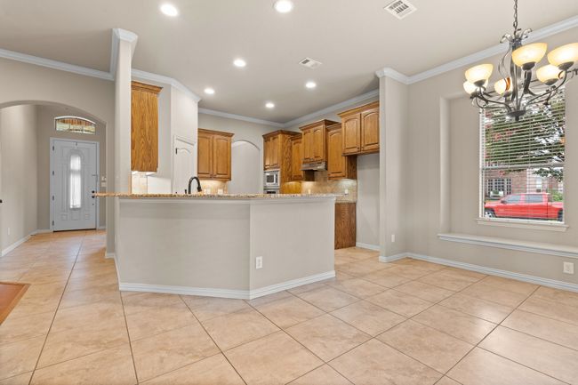 Kitchen featuring light tile patterned floors, a chandelier, arched walkways, crown molding, and decorative backsplash | Image 14