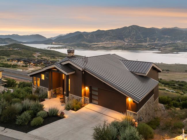View of front of house with a standing seam roof, stone siding, a metal roof, a chimney, and an attached garage | Image 6
