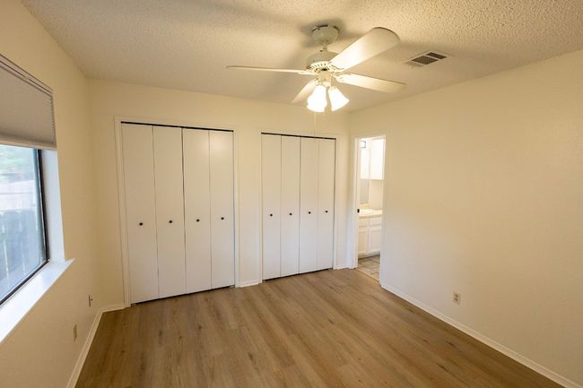 Unfurnished bedroom with light wood finished floors, two closets, multiple windows, baseboards, and a textured ceiling | Image 24