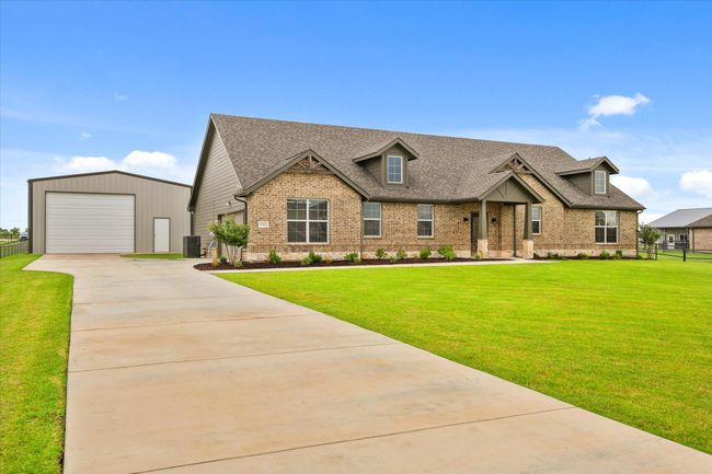 Craftsman-style home featuring brick siding, driveway, roof with shingles, an outbuilding, and a garage | Image 4
