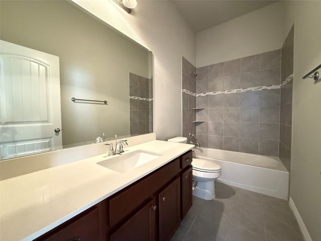 Bathroom with vanity, toilet, tile patterned floors, shower / washtub combination, and baseboards | Image 13